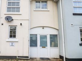Exterior view of a building with a white door and windows with a parking sign for number 1 Ilsham Cottages in Torquay