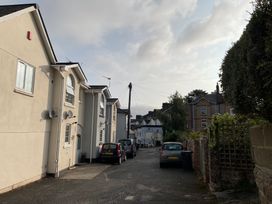 A narrow street with parked cars between residential buildings and a hedge at 1 Ilsham Cottages in Torquay