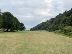 A grassy open field with trees on both sides and a cloudy sky at 1 Ilsham Cottages in Torquay