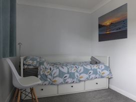 A bedroom with a bed and a chair at 1 Ilsham Cottages in Torquay