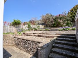 A terraced garden with stone retaining walls wooden steps and flowering shrubs at Bryn Bach in Rhos-On-Sea