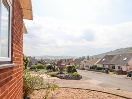 A residential street with houses bushes and hills in the background at Bryn Bach in Rhos-On-Sea