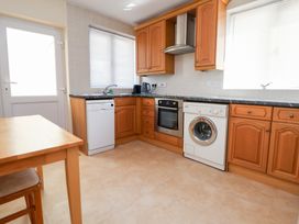 A kitchen with appliances and a table at Bryn Bach in Rhos-On-Sea