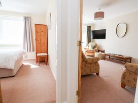 A living room with an armchair and table visible from a doorway at Bryn Bach Rhos-On-Sea