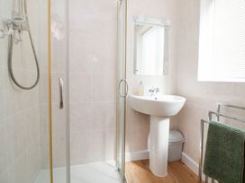 A bathroom with a shower, sink, and mirror at Bryn Bach in Rhos-On-Sea