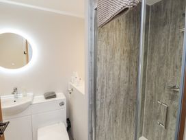 A bathroom with a toilet, sink, mirror, and shower at The Hideaway 