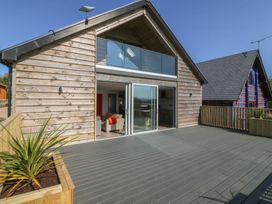A wooden house with a deck and glass doors at The Hideaway in Mynytho near Abersoch