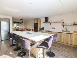 A kitchen with a counter, bar stools, refrigerator, and oven at The Hideaway in Mynytho near Abersoch