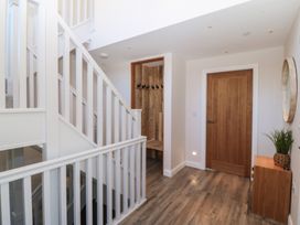 A hallway with a staircase and a bench with coat hooks at The Hideaway in Mynytho near Abersoch