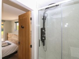 A bathroom with a shower and bed visible at The Hideaway Mynytho near Abersoch