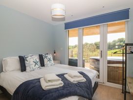 A bedroom with a bed and window looking out to a hot tub at The Hideaway Mynytho near Abersoch