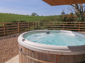A hot tub on a wooden deck with a view of grassy landscape at The Hideaway in Mynytho near Abersoch