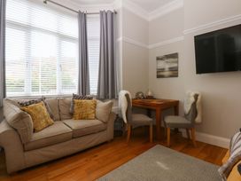 A living room with a sofa and dining table at Queens Park in Llandudno