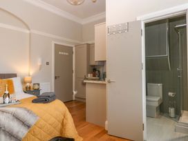 A bedroom with a bathroom door and kitchen amenities at Queens Park in Llandudno