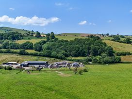A farm with buildings and trees in a field at Hay Store in Corwen