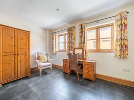 A bedroom with a wardrobe, desk and armchair at Hay Store in Corwen