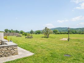 An outdoor area with picnic tables and a stone wall at Hay Store in Corwen