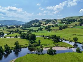A landscape view of fields and a river at The Barn in Corwen