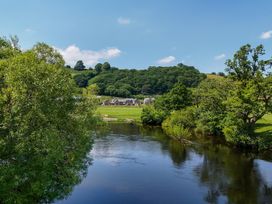 A view of a river with trees and houses on the bank at The Barn in Corwen