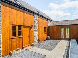 An outdoor view of a wooden structure with a stone wall and pathway at The Barn in Corwen