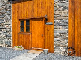 A rustic entrance with wooden door and stone wall at The Barn in Corwen