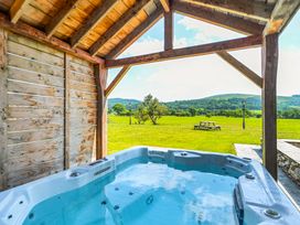 A hot tub under a wooden structure in an outdoor area at The Barn in Corwen
