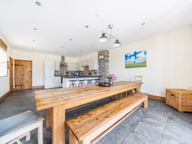 A dining room with a wooden table and kitchen area at The Barn in Corwen