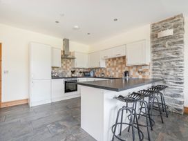 A kitchen with bar stools and appliances at The Barn in Corwen