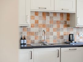A kitchen with tiles and a sink at The Barn in Corwen