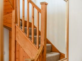 A staircase with wooden handrail and carpet at The Barn in Corwen
