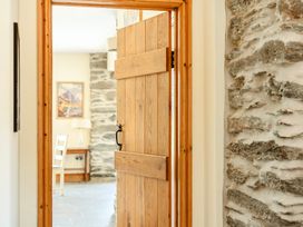 A wooden door opening to a hallway with a table and chair at The Barn in Corwen