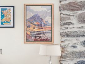 A framed poster and a map on a wall next to a lamp at The Barn in Corwen