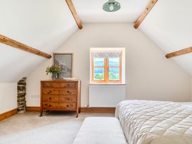 A bedroom featuring a bed, dresser, window, and flower arrangement at The Barn in Corwen