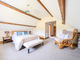 A bedroom with a bed and armchair at The Barn in Corwen