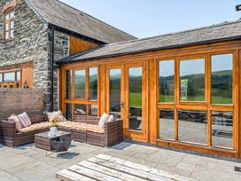 An outdoor seating area with a rattan sofa and table at The Barn in Corwen