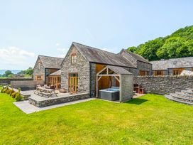 A house with a hot tub and patio furniture in the garden at The Barn in Corwen