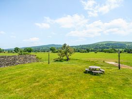 A garden with a picnic table and tree at The Barn in Corwen