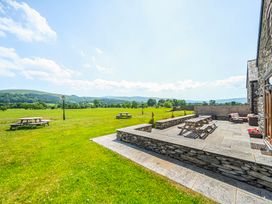 An outdoor area with picnic tables and a stone patio at The Barn in Corwen