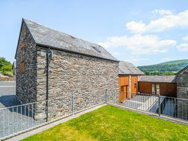 An outdoor area with stone and wooden houses at The Barn in Corwen
