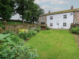 A garden with a house and stone wall at The LA'AL Cragg in Kirkby Stephen