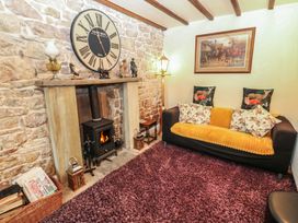 A living room with a sofa and clock on the wall at The LA'AL Cragg in Kirkby Stephen
