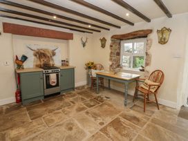 A kitchen with a stove and table at The LA'AL Cragg in Kirkby Stephen