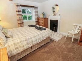 A bedroom with a bed, dresser, window, and fireplace at The LA'AL Cragg in Kirkby Stephen
