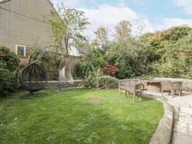 A garden with hanging chairs and a wooden table at The Old Hall in Tetbury