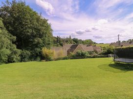 A garden with a trampoline and houses in the background at The Old Hall Westonbit Nr Tetbury