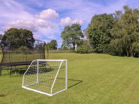 A trampoline and soccer goal on grass at The Old Hall in Westonbit Nr Tetbury