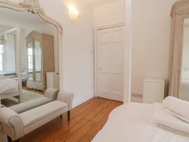 A bedroom with a bed, chair, wardrobe, and mirror at Scillonia, Penzance