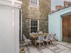 A patio with a wooden table and chairs at Scillonia in Penzance