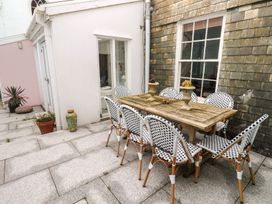An outdoor dining area with a wooden table and chairs at Scillonia in Penzance