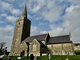 A church with a tower and gravestones near Pembroke at Tower Cottage